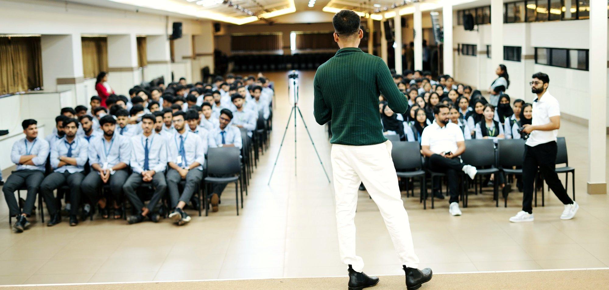 Roni Paul addressing a hall of students at a college talk